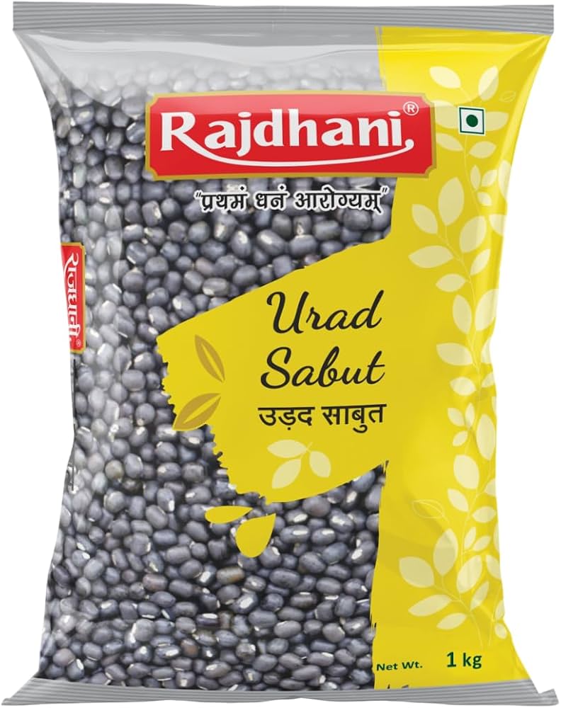 A 1 kg bag of Rajdhani Urad Sabut (black lentils) in its original packaging, featuring a yellow and white design with a clear window showing the dark gray-black lentils inside.